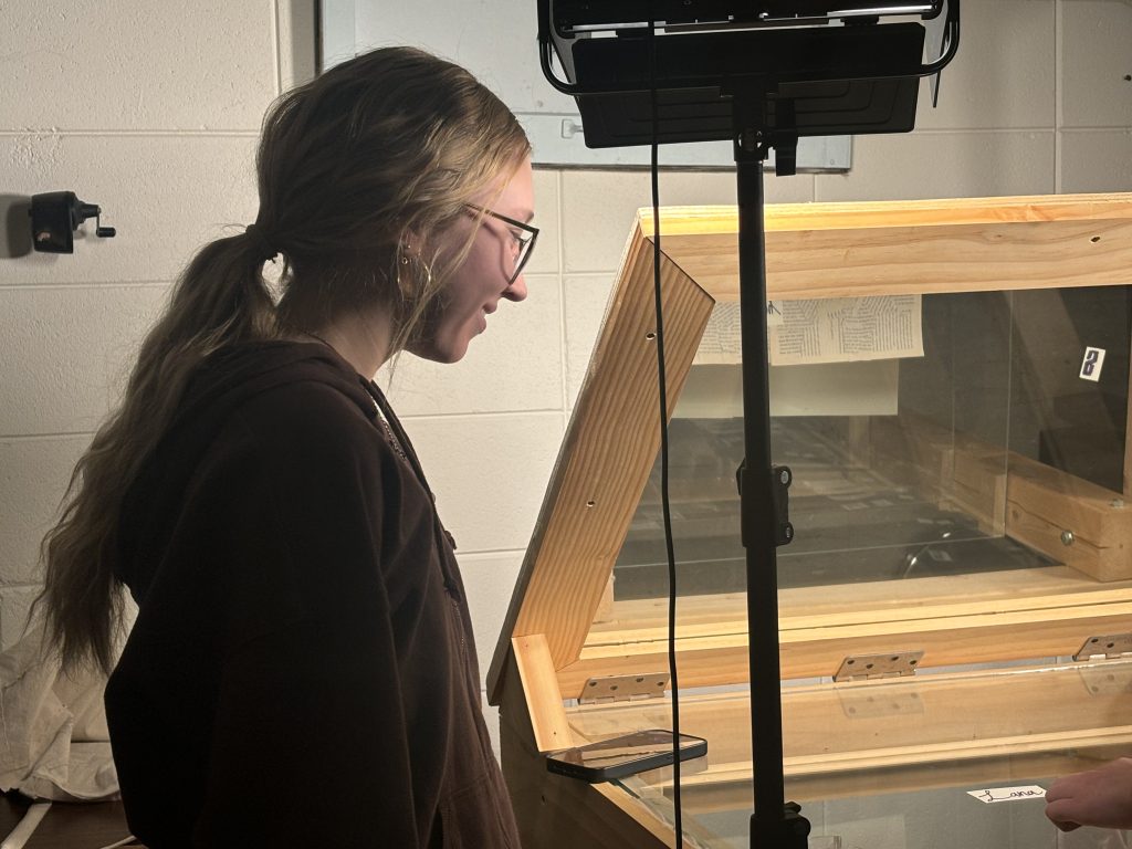 Alice standing next to light kit as Reece prepares to film.